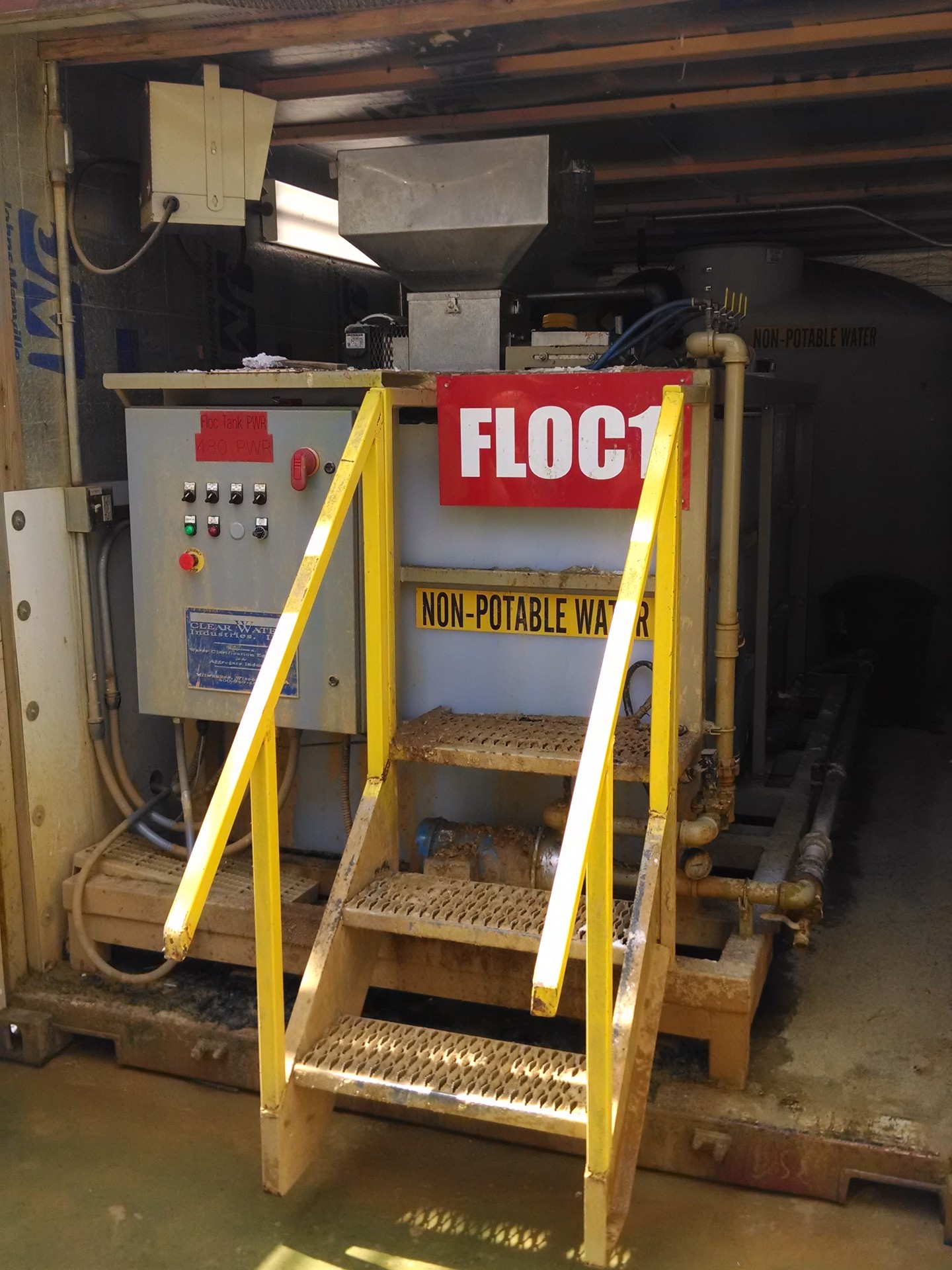 An older and dirty dry polymer make-down system housed in a shipping container at an aggregate production site.