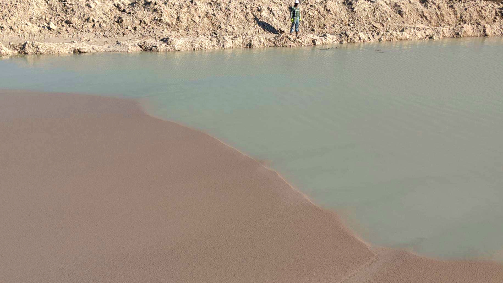 A pond with a clear line where the dirty water stops and clean water begins due to particles falling out of liquid suspension.