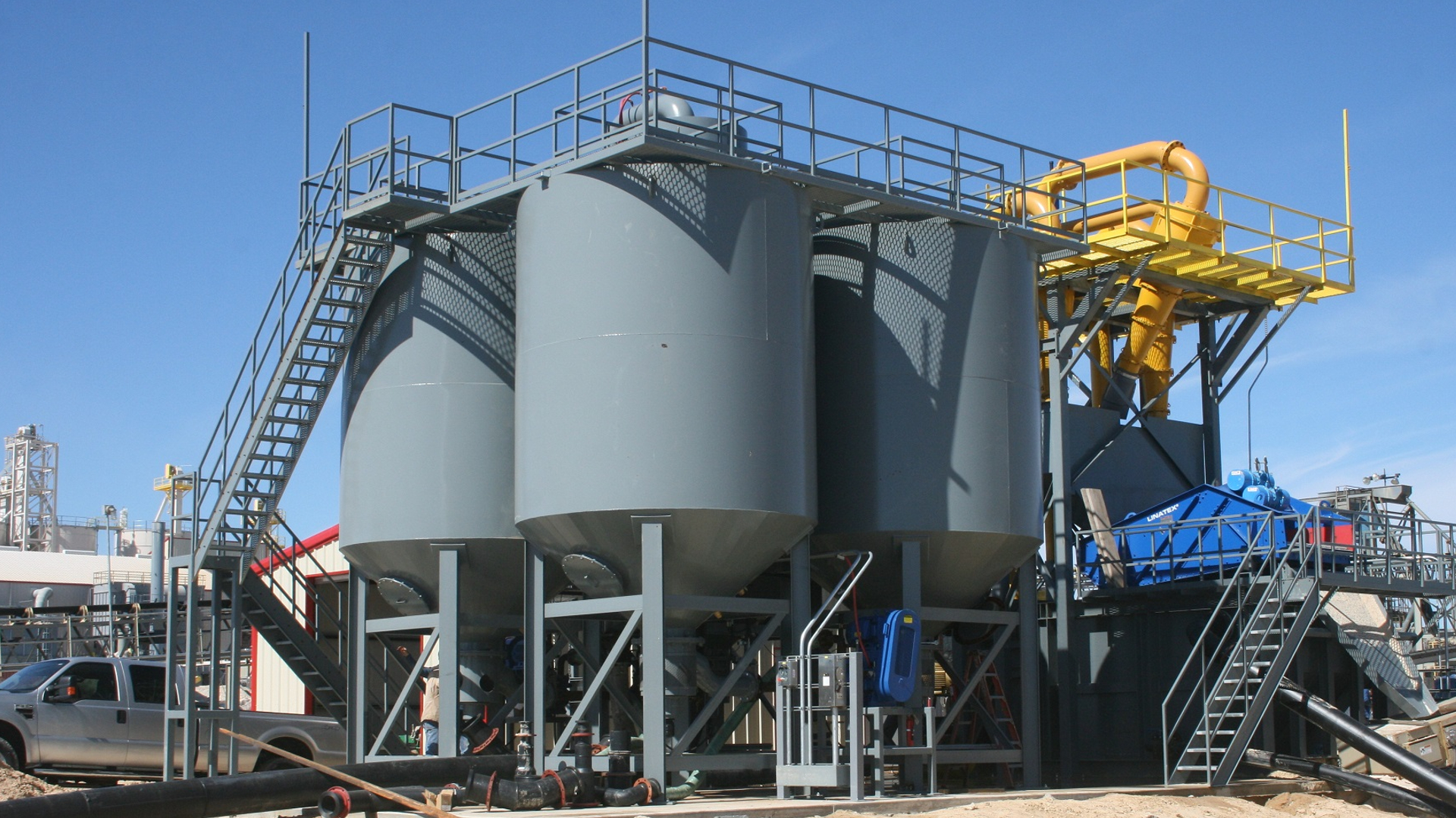 Three vertically oriented grey industrial clarifiers outside.