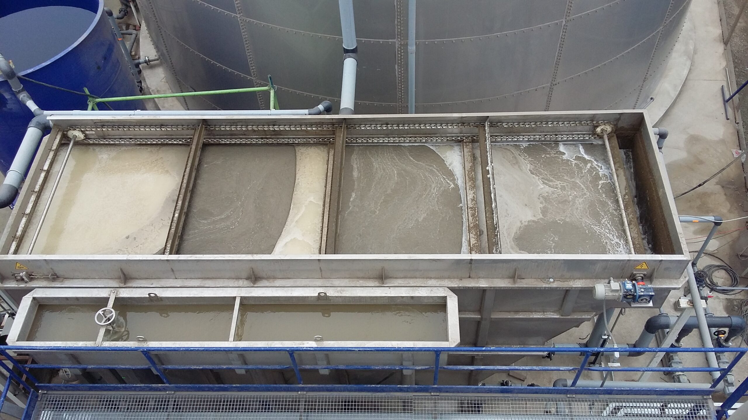 An aerial view of the top of a DAF clarifier filled with brown wastewater and floating sludge.