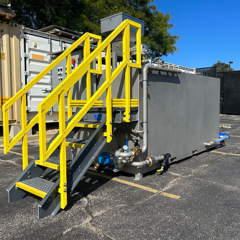 Clearwater Industries standard M-Series dry polymer make-down system pictured from the side to display the 304SS rectangular tank and dilution water plumbing with a flowmeter, booster pump, solenoid valve, fittings, and valves.